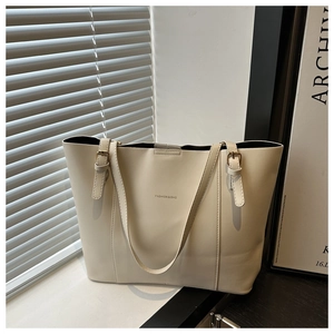 Close-up of cream PU leather tote bag featuring gold hardware and logo printing