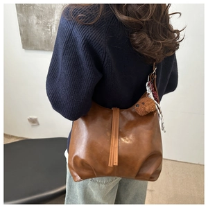Brown faux leather tote bag with teddy charm on model in a minimalist setting