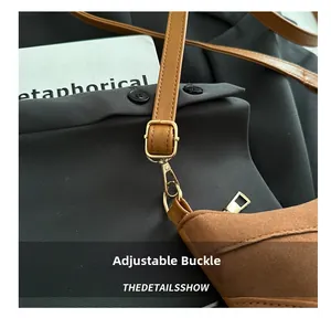 Detail of tan suede tote bag featuring polished gold hardware and adjustable strap buckle