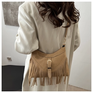 Close-up of bohemian brown suede shoulder bag featuring long fringe tassels and golden buckle