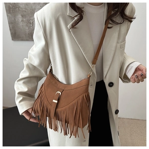 Detail of vintage brown suede crossbody bag featuring long bohemian tassels and buckle strap