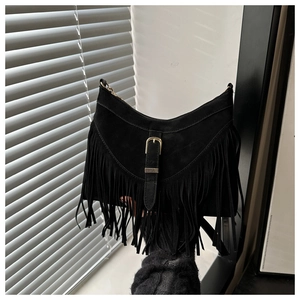 Detail of bohemian black suede shoulder bag featuring long fringe and gold metal buckle