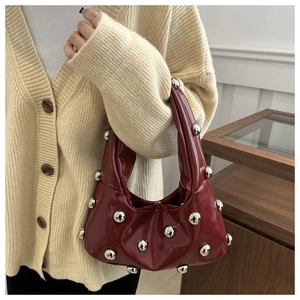 Close-up of a burgundy glossy underarm bag featuring silver rivet ball studs and hardware