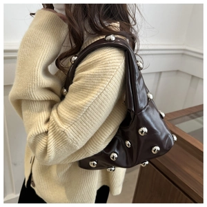 Détail d'un sac sous les bras en cuir marron foncé avec rivets sphériques argentés