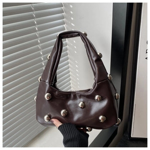 Détail du sac hobo en cuir café foncé avec gros clous sphériques argentés et anse plissée