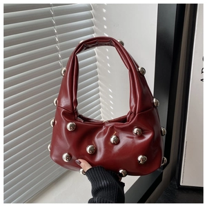 Détail du sac à bandoulière bordeaux froncé avec de gros clous à boules argentées