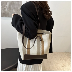 Detail view of large canvas tote bag featuring brown stripes and faux leather handles