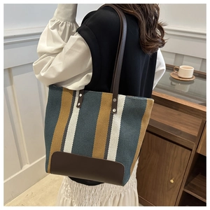 Close-up of canvas texture and brown leather trim on striped oversized tote bag