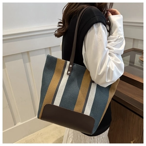 Detail of canvas tote bag with colorful vertical stripes and brown leather straps
