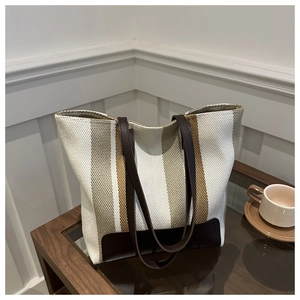 Detail view showing textured vertical stripes and leather handles of the tote bag