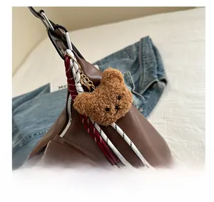 Detail of plush bear charm with red rope tassel on vintage brown leather tote bag