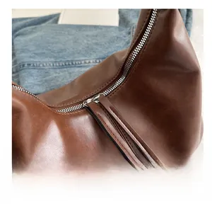 Close-up of smooth metal zipper and leather tassel on brown vintage tote bag