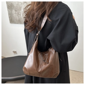 Detail of a brown retro hobo bag showing its leather texture and long tassel zipper puller