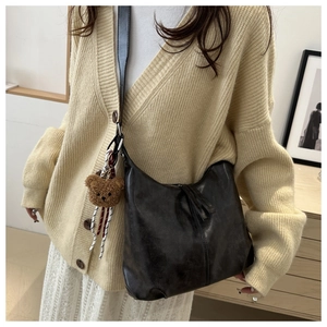 Detail of dark brown leather hobo bag with fringe zipper and cute teddy bear charm