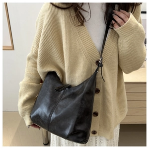 Close-up of black retro leather hobo bag with adjustable strap on a female model
