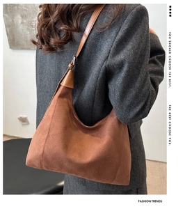 Brown suede hobo tote bag shown from side view on a model with grey suit