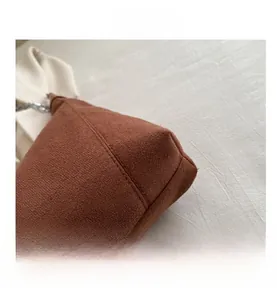 Close-up of brown suede tote bag featuring rounded corners and fine stitching detail
