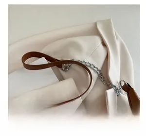 Detail of brown leather and silver chain shoulder strap with metallic buckle on a tote bag