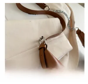 Detail of adjustable brown leather shoulder strap with silver buckle and metal chain link