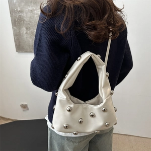 White crescent shoulder bag with silver rivet studs and polished finish on a model