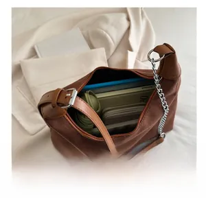 Macro shot of brown suede tote bag showing large capacity with wallet and notebook