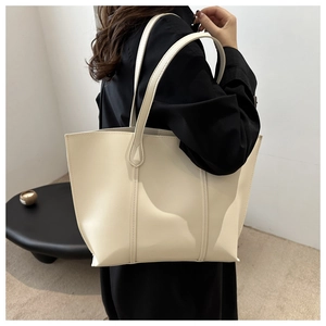 Detail view of large cream leather tote bag with elegant stitching and shoulder straps