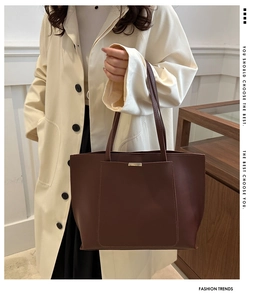 Detailed view of dark brown leather tote bag with elegant gold metal trim and stitching