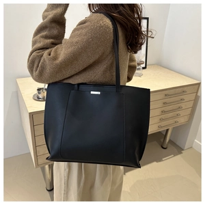 Detail showing high-capacity black leather tote bag with elegant metal hardware decoration