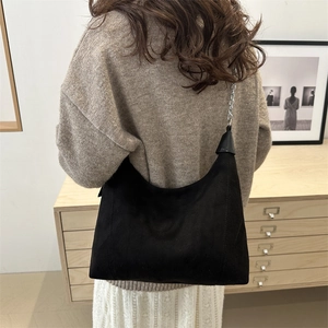 Chic black faux suede crescent hobo bag with silver chain strap worn by a model