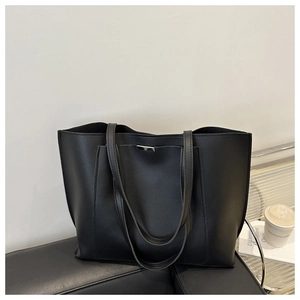 Detailed macro view of the silver metal buckle on a black leather minimalist tote bag