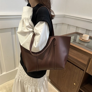 Grand sac cabas en cuir marron foncé porté par un mannequin dans un intérieur élégant