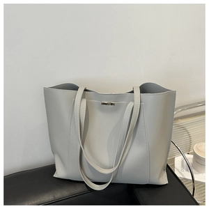Close-up of minimalist light grey tote bag featuring slim straps and silver metal hardware