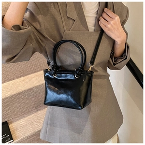 Détail du mini sac à main noir brillant avec ferrures dorées et bandoulière amovible