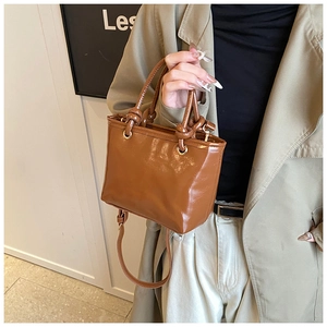 Détail du sac seau marron verni avec poignées nouées et boucles métalliques dorées