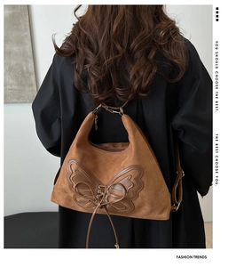 Detail of caramel suede tote bag featuring a leather butterfly patch and cross-lace design