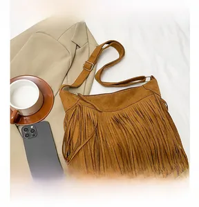 Detail of brown suede tassel crossbody bag with adjustable strap and top zipper closure
