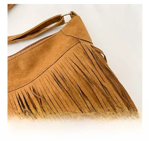 Detail shot of brown faux suede fringe shoulder bag with zipper and golden metal ring