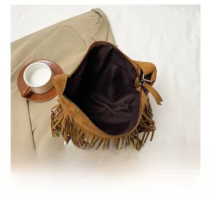 Detail view of the brown suede fringe bag interior showing the brown fabric lining and zip