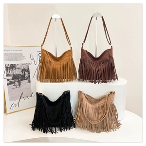 Detail view of four fringe shoulder bags in suede finish hanging on a metal rack