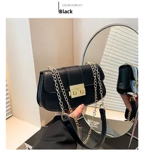 Détail du sac à bandoulière noir avec fermoir doré et bandoulière chaîne sur un miroir