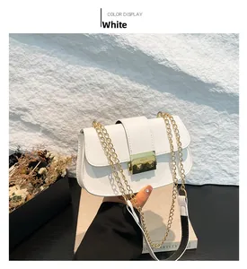 Détail du sac selle blanc avec fermoir doré et bandoulière en chaîne métallique