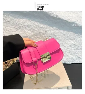 Détail du sac baguette en cuir mat rose rouge avec chaîne dorée et fermoir rotatif