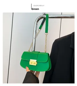 Détail du sac baguette en cuir vert avec chaîne dorée et fermoir sur un blazer noir