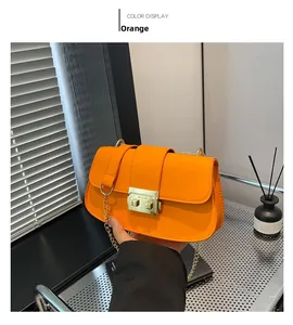 Détail d'un sac à bandoulière en cuir orange avec chaîne dorée et fermoir carré élégant