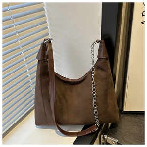 Detail of dark brown suede tote bag with silver chain and metal buckle accents