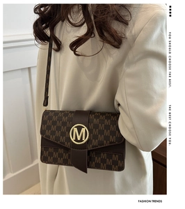 Détail du sac à bandoulière marron avec motif de lettres M et boucle en métal doré