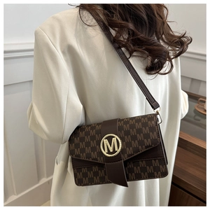 Close-up of brown monogram crossbody bag with golden M metal buckle and retro texture