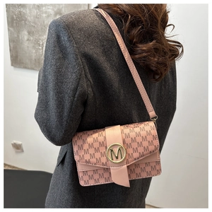 Detail of pink shoulder bag featuring golden M-logo clasp and all-over letter print