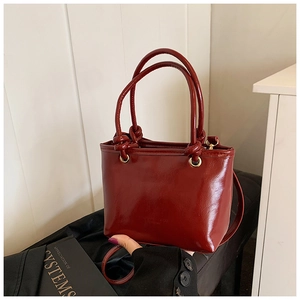 Détail du sac cabas en cuir bordeaux avec poignées à nœuds et œillets en métal doré