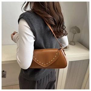 Close-up of brown vintage shoulder bag featuring gold rivets and sleek leather texture